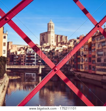 a view of Girona, in Spain, the Onyar River and the Old Town of the city, highlighting the Cathedral on the right, seen through the structure of the characteristic red bridge built by Eiffel