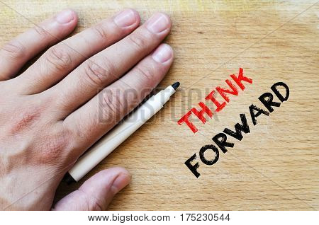 Human hand over wooden background and think forward text concept