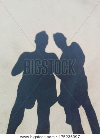 Long shadow of two friends on beach sand