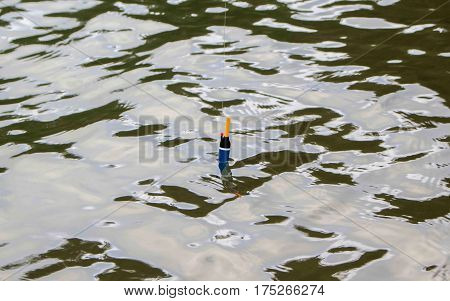 Fishing float in water. Rippled water of forest lake. Fishing weekend concept photo. Waiting for fish to nibble. Fishing with rod image. Fishing tackle in water. Active holiday outdoor hobby picture