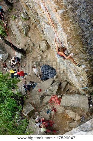 Ein eifrig weiblichen Kletterer auf eine steile Felswand sieht für die nächsten Halt - von oben gesehen.  Flache d