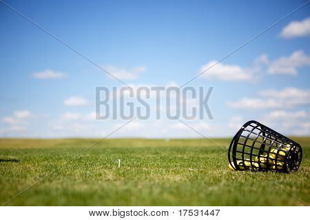 En tee og gule golfbolde på en driving range