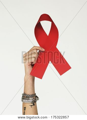 Hand holding red ribbin to support cancer patient