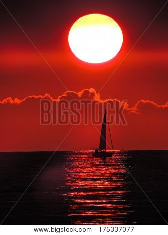 Sailboat passing under the setting sun at Waikiki Beach