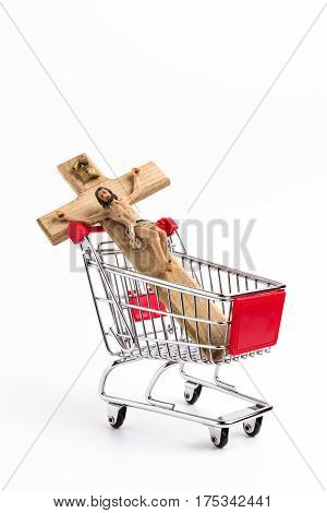 Crucifix in shopping cart. Conceptual representation of commodification of religion loss of faith blasphemy.