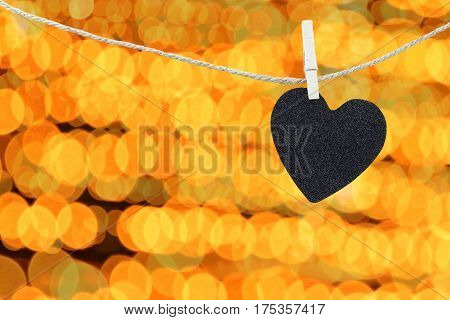 Black Heart hung on hemp rope on abstract colorful bokeh background and have copy space to manage the text you want.