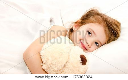 Adorable little girl in the bed with her toy