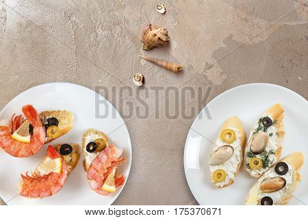 Beautiful snapshots of various italian sandwiches with seafood arranged on rustic wooden background with plates with food and seashells with copy space horizontal top view.