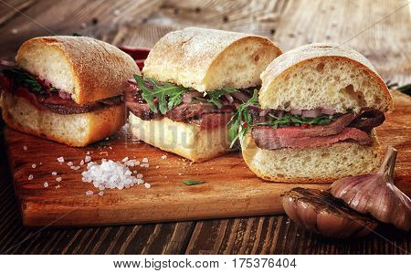 Sandwich With Beef Steak On A Wooden Stand.