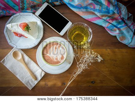coffee cup and delicious cake strawberry and relax time moblie on table in coffee shop