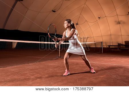 Sportswoman at the tennis court with racquet. Indoor tennis court