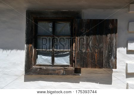 Wooden window with a shutter on the white wall of the house