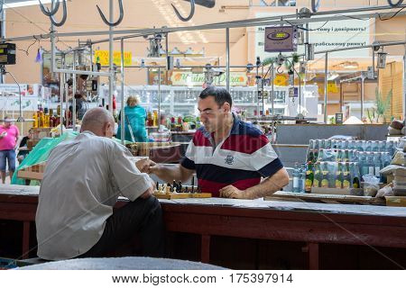 KIEV UKRAINE - AUGUST 17 2015: Butchers playing chess next to the meat they are selling inside Besarabsky market one of the iconic markets of Kiev