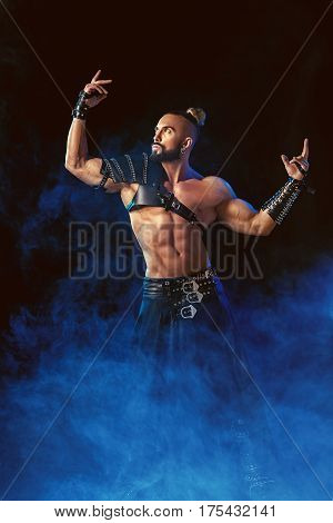 Young and muscular man performing a theatrical pose on stage. Striptease. Handsome man