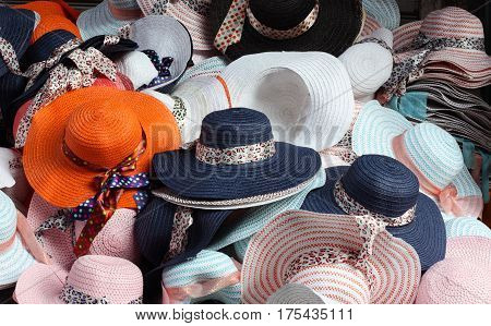 Summer fashion hats piled high at an Asian outdoor market stall.