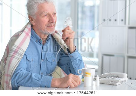 Portrait of a sick elderly man makes inhalation