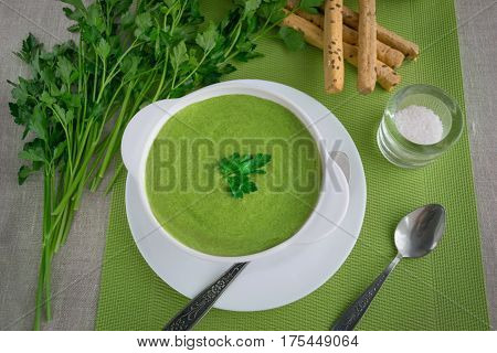 Spinach cream soup with parsley and breadsticks