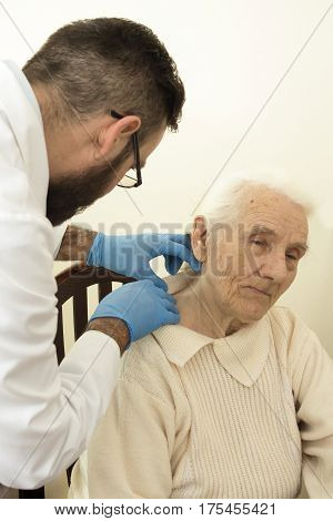 The doctor geriatrician during the test. 
Doctor examines changes in the skin of an old woman.