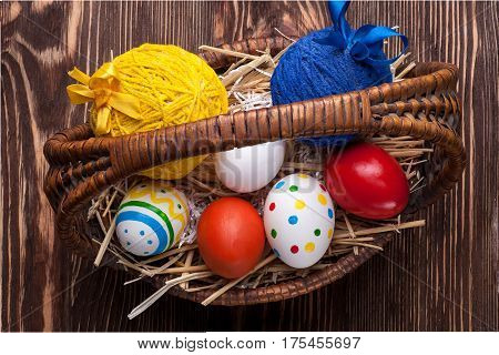 Colorful easter edds in basket on a brown wooden table
