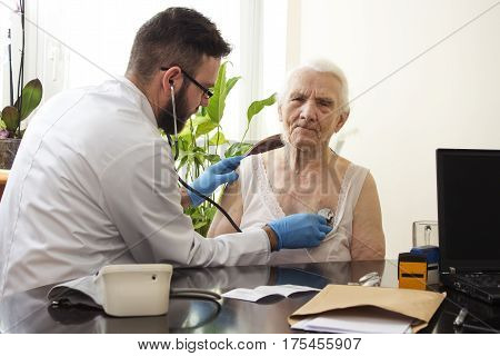 Doctor examining an old woman with a stethoscope in a doctor's office.
Medical examination with a stethoscope. Geriatrician doctor examining lungs.
