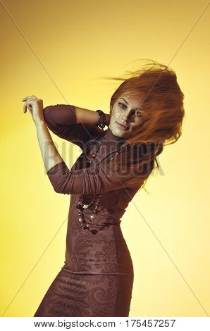 Colorful studio portrait of a beautiful young woman with flowing hair on a yellow background