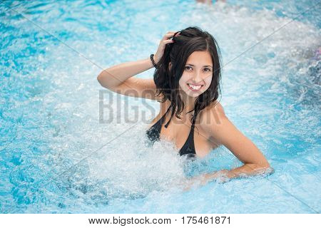 Young Brunette Female In A Black Bathing Suit With A Snow-white Smile Relaxing In A Jacuzzi