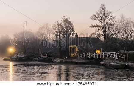 Kalenberg and the Kalenbergergracht during sunrise with farmhouses boats a bridge and ducks.