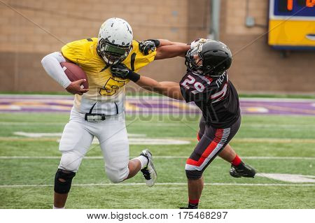 Football cornerback fighting through a stiff arm from wide receiver.