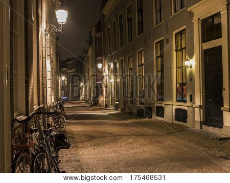 Deventer The Netherlands - December 172016: Bicycles against the old wall in the evening with lanterns in the Polstraat (street) in Deventer.