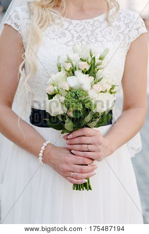 Bride holding delicate and tender marriage bouquet in white and green colours