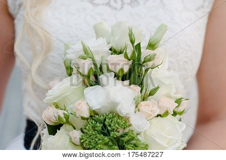 Bride holding delicate and tender marriage bouquet in white and green colours