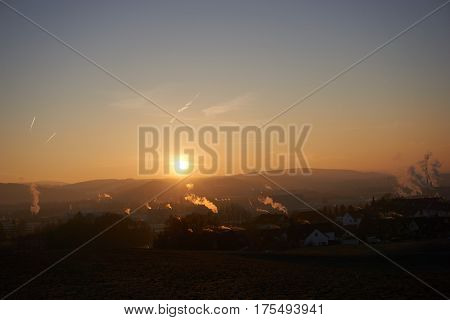 sunset with smoke and condensation trails on a business day