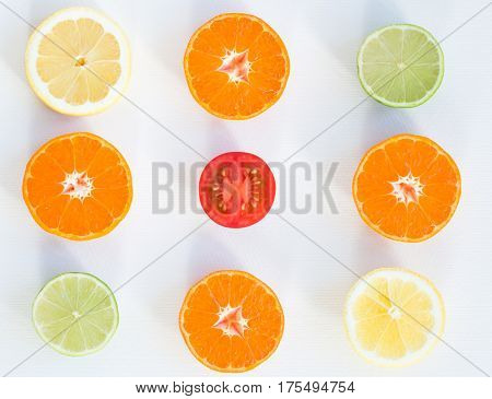 Top view of eight slices of citrus fuits and one slice of tomato on the white background