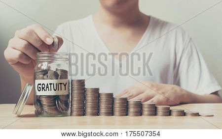 Hand putting coins in jar word gratuity with money stack step growing growth saving money Concept finance business investment