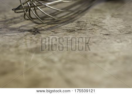 Closeup of metal wisk on marbled kitchen counter background with space for text