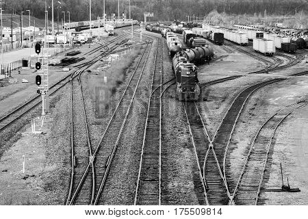 Busy trainyard with many trains on multiple switching tracks in black and white