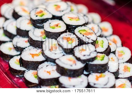 Close up of a plate full with sushi rolls.