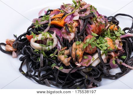 Black spaghetti with seafood and vegetables isolated on white