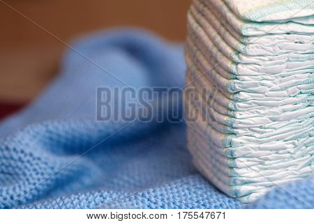 Stack of diapers or nappies on blue knitted blanket closeup