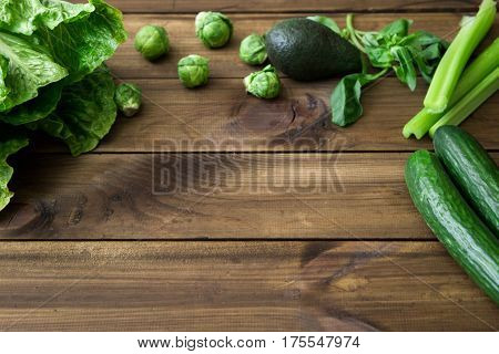 Products containing folic acid - B9 vitamin . Green vegetables on dark wooden background. Celery, avocado, Brussels sprouts, basil, cucumber romaine salad. space for text