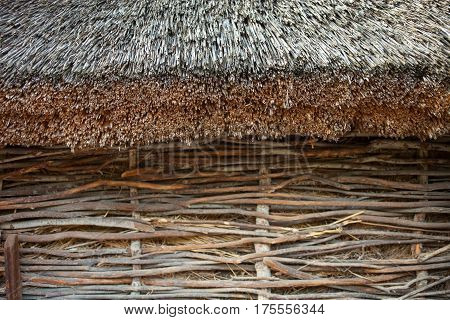 Wattle wall of the shed with straw-thatched roof. Old traditional Ukrainian architecture.