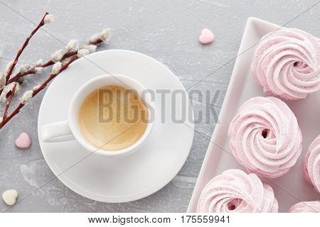 Cup of espresso coffee and homemade zephyr or marshmallow in a white plate on stone background