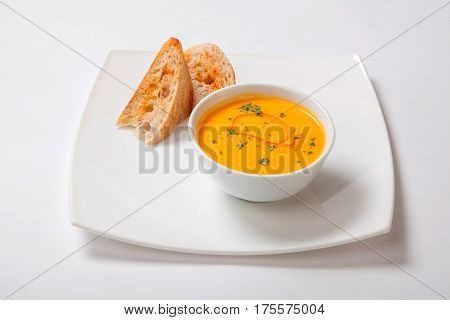 Pumpkin Cream Soup In White Bowl With Slices Of White Bread