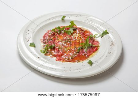 Beef Carpaccio Garnished With Fresh Arugula On White Plate