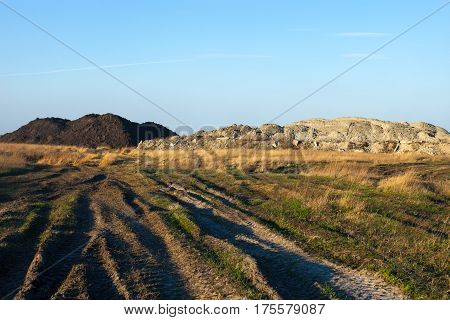 Dirt road in the field. Earth embankments in the background.