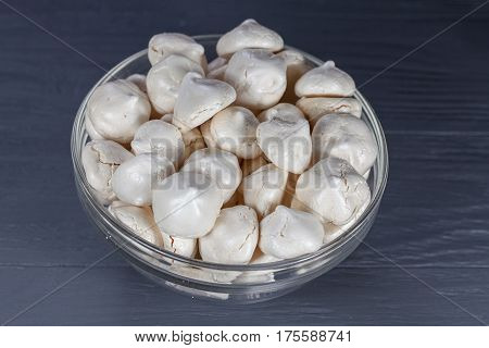 White mini meringue in transparent vase on a wooden background, top view