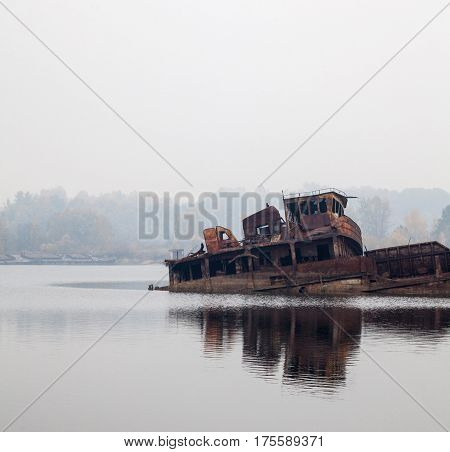 Old rusty sunken ship in water in a foggy day.