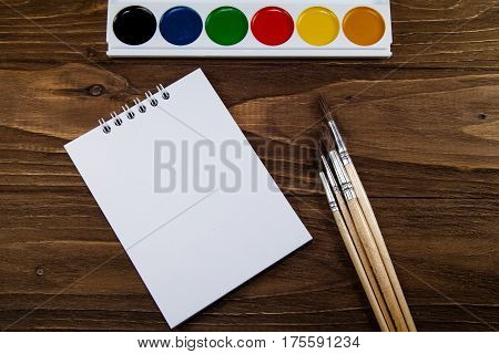 Art palette with brushes and paints on a wooden background