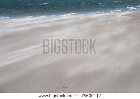 Beach with sand flying and sea. Can be used as background.
