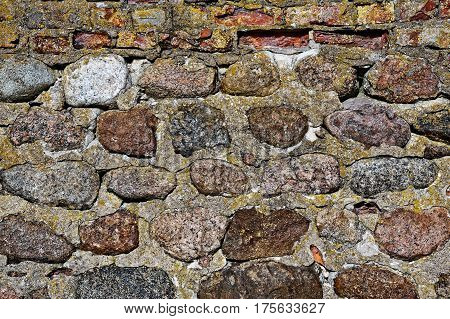 The old wall of granite stones. Foundament.